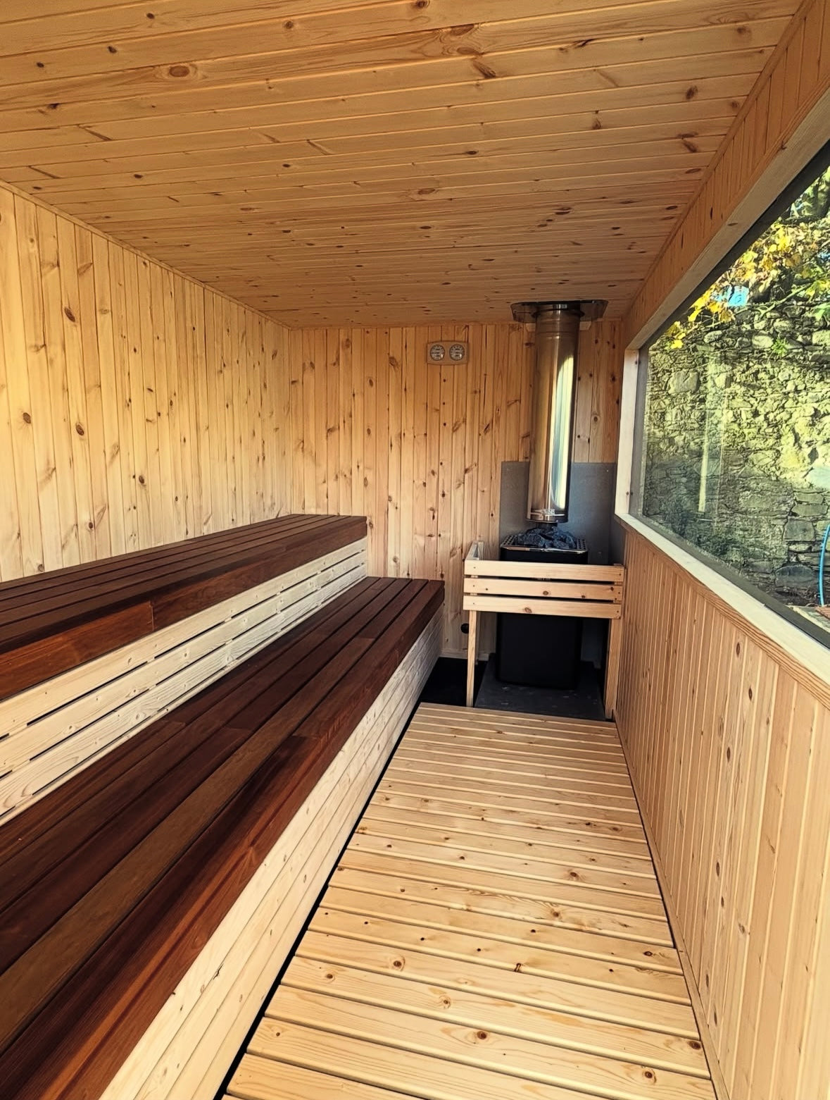 Wooden sauna interior with benches and a stove.